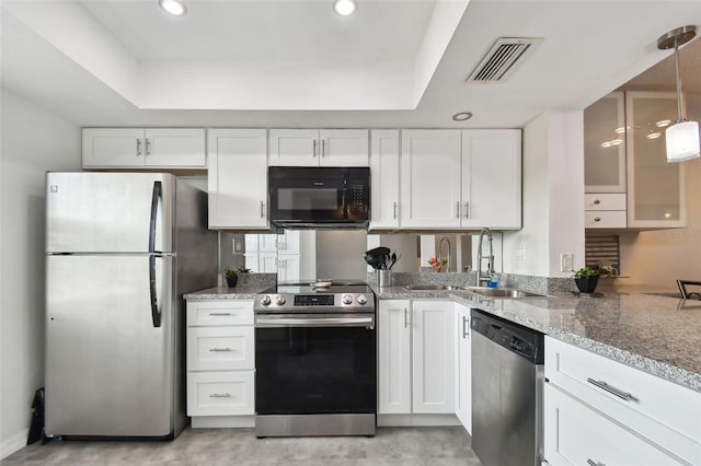 kitchen with pendant lighting, white cabinetry, appliances with stainless steel finishes, and a tray ceiling