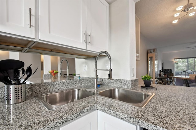 kitchen featuring white cabinets, ceiling fan, light stone countertops, and sink