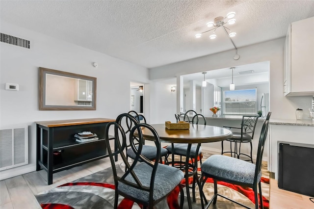 dining area with a textured ceiling, light hardwood / wood-style floors, and ceiling fan