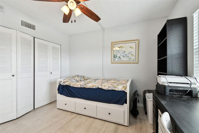 bedroom featuring ceiling fan, a closet, a textured ceiling, and light wood-type flooring