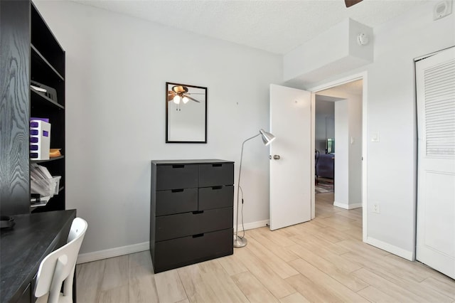 office space featuring ceiling fan, light hardwood / wood-style floors, and a textured ceiling