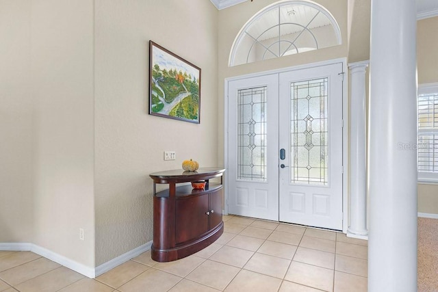 tiled entryway featuring ornate columns and crown molding