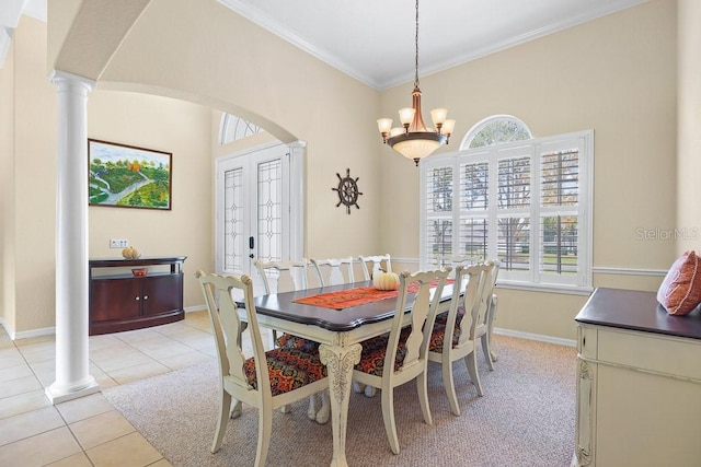 tiled dining room with ornamental molding, an inviting chandelier, a healthy amount of sunlight, and ornate columns