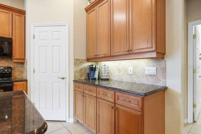 kitchen with black appliances, light tile patterned floors, backsplash, and dark stone counters