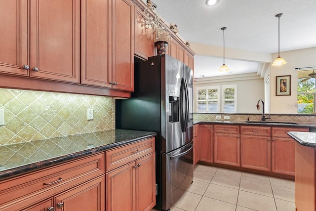 kitchen featuring dark stone counters, a wealth of natural light, sink, and hanging light fixtures