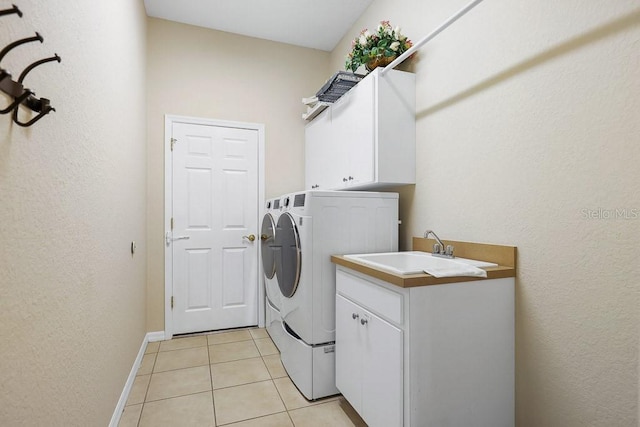 laundry area with light tile patterned flooring, cabinets, sink, and washing machine and clothes dryer