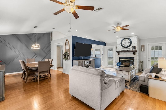 living room with ceiling fan, plenty of natural light, a fireplace, and light hardwood / wood-style flooring