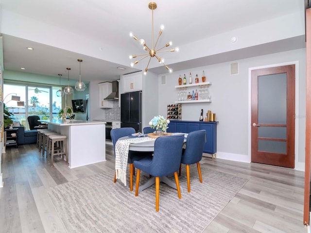 dining space featuring a notable chandelier, indoor wet bar, and light hardwood / wood-style flooring