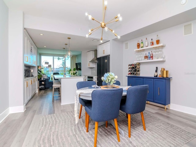 dining area with indoor wet bar, light wood-type flooring, and a chandelier