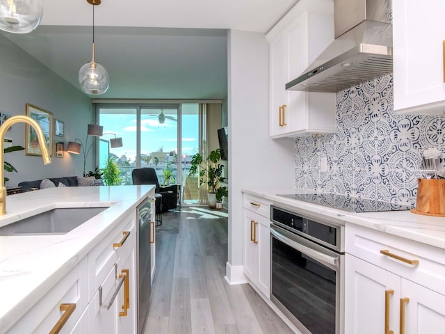 kitchen featuring sink, wall chimney exhaust hood, stainless steel appliances, light hardwood / wood-style flooring, and white cabinets