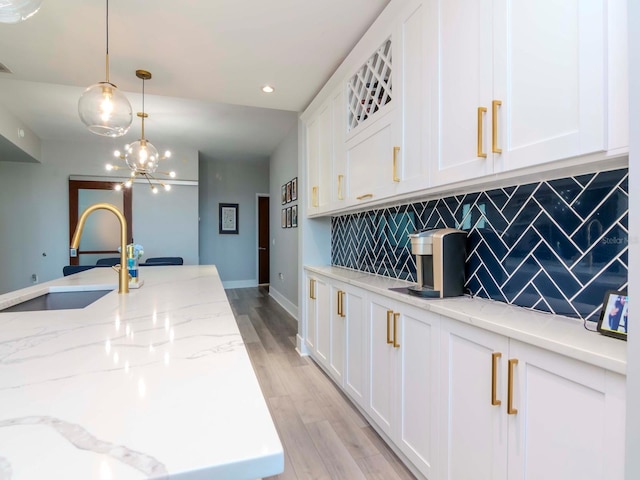 kitchen with light stone countertops, sink, pendant lighting, light hardwood / wood-style floors, and decorative backsplash