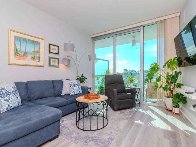 living room featuring light hardwood / wood-style flooring, a wall of windows, and ceiling fan