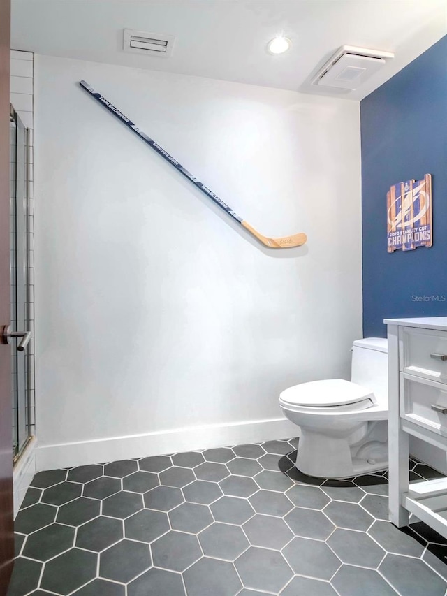 bathroom with tile patterned flooring, vanity, toilet, and a shower with shower door