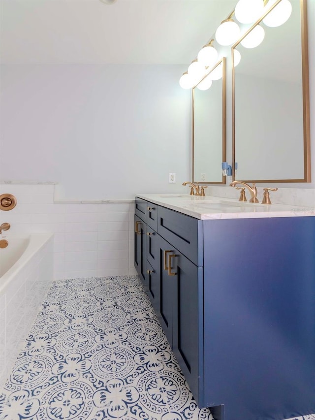 bathroom featuring tile patterned floors, tiled tub, vanity, and tile walls