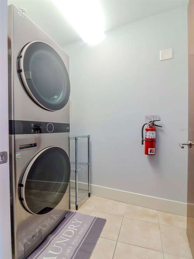 washroom with light tile patterned floors and stacked washing maching and dryer