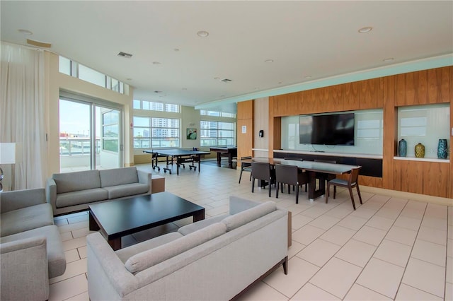 tiled living room featuring a healthy amount of sunlight and wood walls