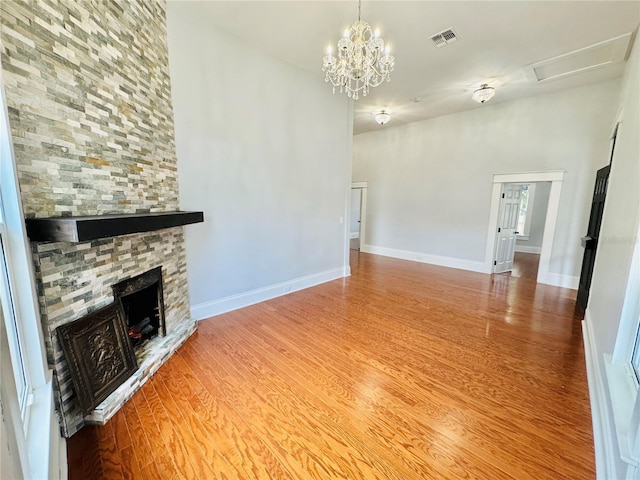 unfurnished living room with a fireplace, hardwood / wood-style flooring, and an inviting chandelier