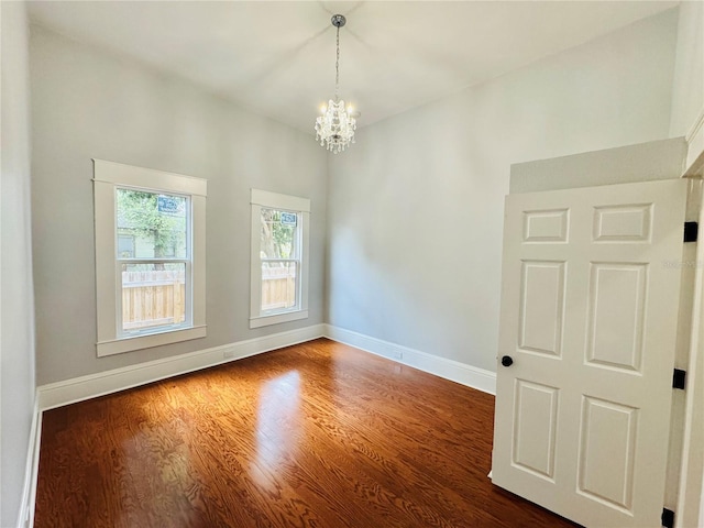 unfurnished room with a chandelier and dark hardwood / wood-style floors