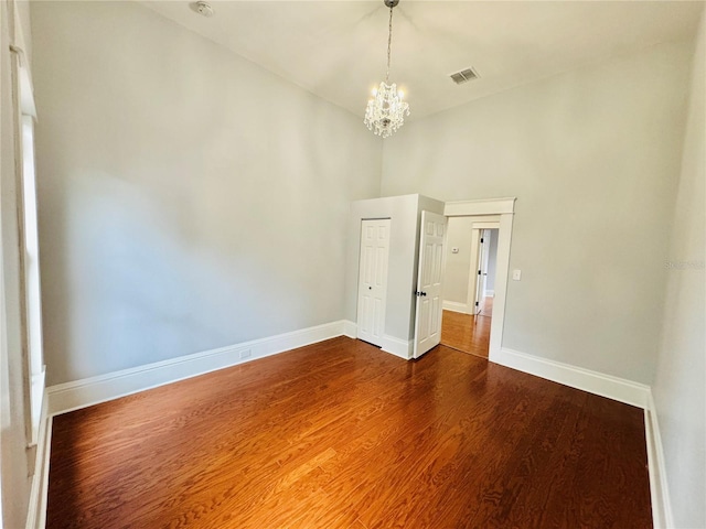 unfurnished room with hardwood / wood-style flooring and an inviting chandelier