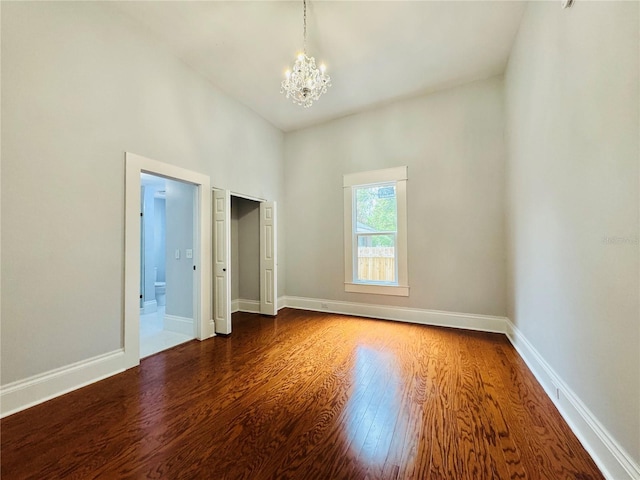 unfurnished room with a chandelier and dark hardwood / wood-style floors