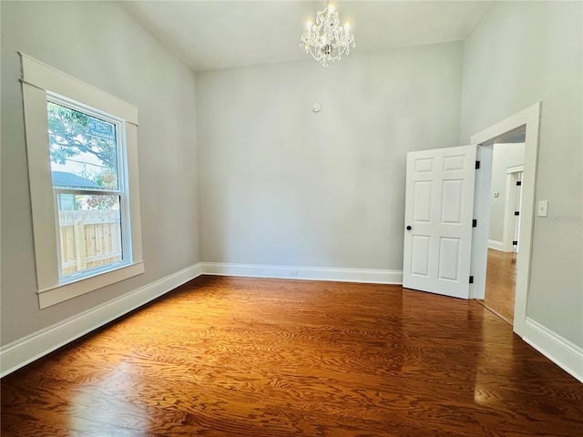 spare room with dark hardwood / wood-style floors and a chandelier