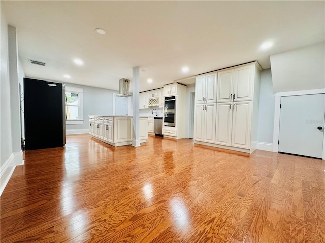 unfurnished living room featuring sink and light hardwood / wood-style flooring