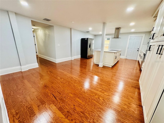 kitchen featuring island exhaust hood, white cabinetry, light hardwood / wood-style flooring, and stainless steel refrigerator with ice dispenser