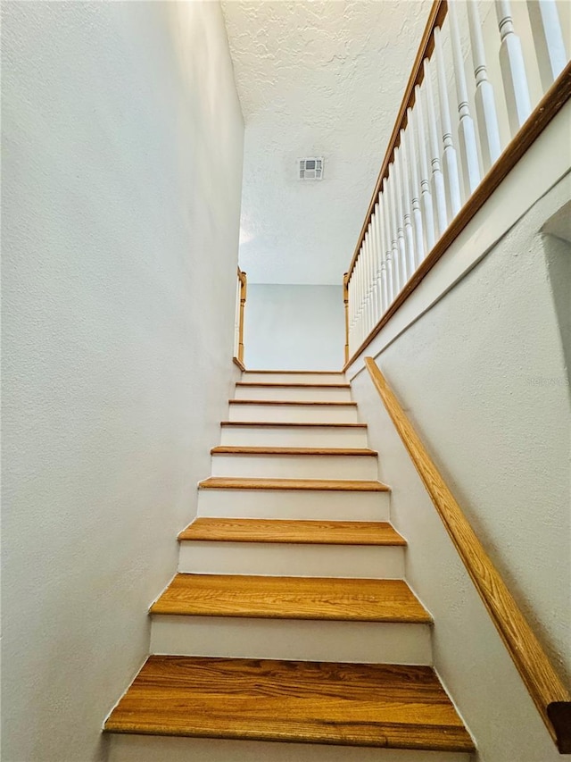 stairs with a textured ceiling