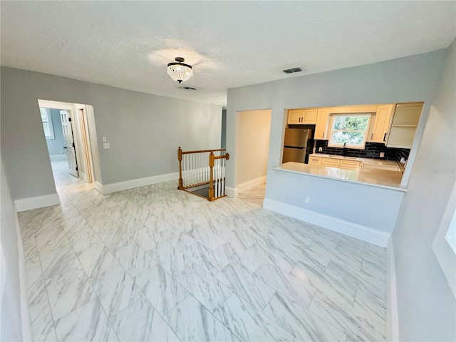 kitchen with decorative backsplash, stainless steel fridge, light brown cabinetry, a textured ceiling, and sink