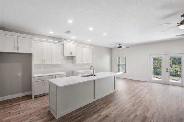 kitchen featuring sink, white cabinetry, an island with sink, ceiling fan, and light hardwood / wood-style floors