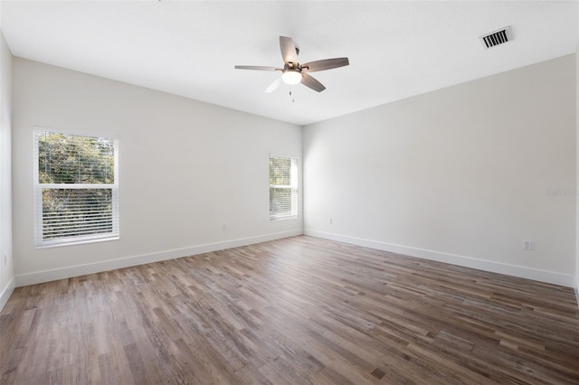 empty room featuring baseboards, wood finished floors, visible vents, and ceiling fan