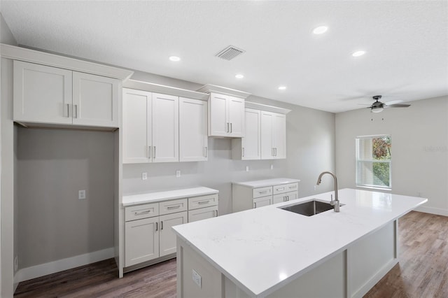 kitchen with visible vents, a center island with sink, white cabinets, a ceiling fan, and a sink