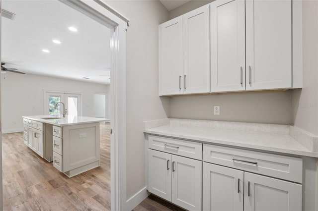 kitchen featuring ceiling fan, light wood-style flooring, visible vents, and a sink