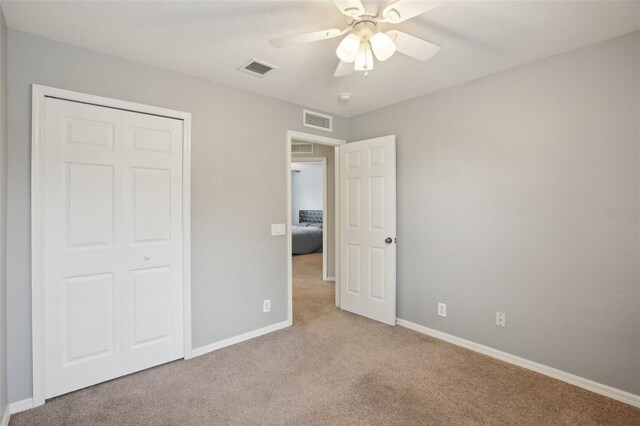 unfurnished bedroom featuring ceiling fan, a closet, and light colored carpet