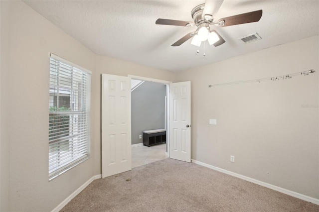 carpeted spare room featuring a textured ceiling and ceiling fan