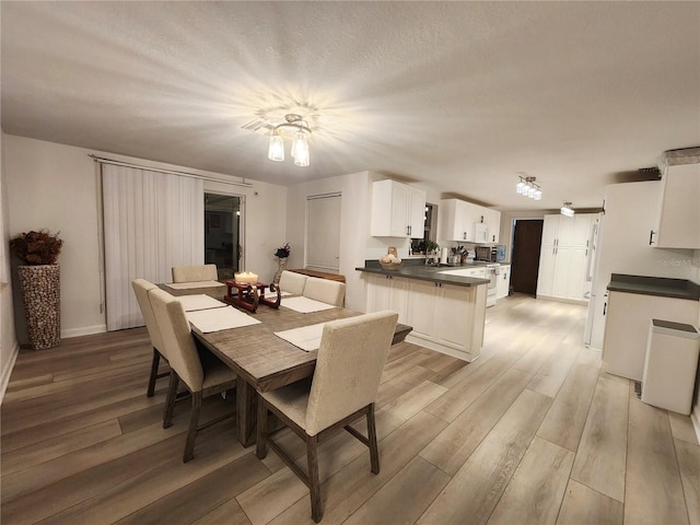 dining room featuring sink, light hardwood / wood-style floors, and a textured ceiling