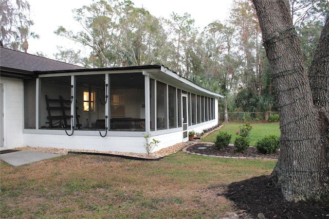 view of home's exterior with a sunroom and a yard