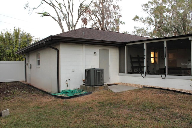 back of property with a sunroom, cooling unit, and a lawn