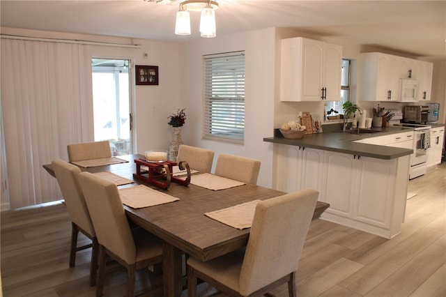 dining space featuring sink, light hardwood / wood-style floors, and a notable chandelier