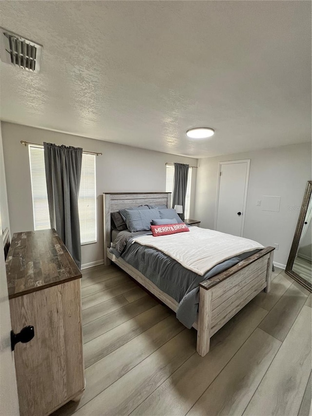 bedroom with hardwood / wood-style floors and a textured ceiling