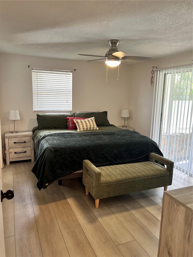 bedroom with access to exterior, a textured ceiling, light hardwood / wood-style flooring, and ceiling fan