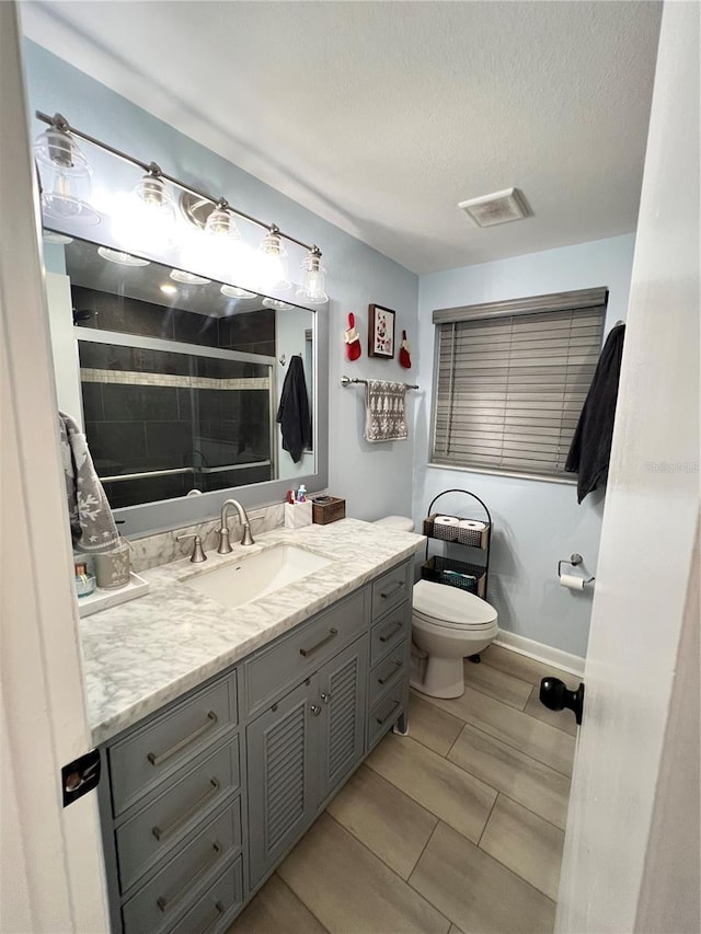 bathroom with vanity, a shower, toilet, and a textured ceiling