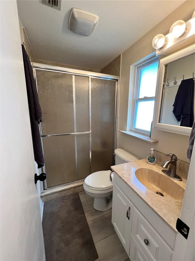 bathroom with tile patterned floors, a textured ceiling, toilet, vanity, and a shower with shower door