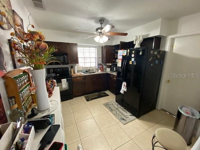 kitchen featuring black appliances, sink, ceiling fan, light tile patterned floors, and dark brown cabinetry