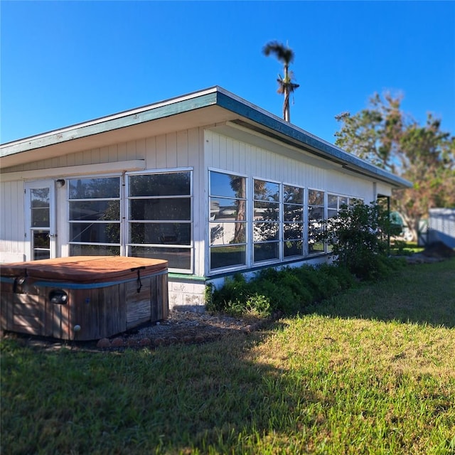 view of side of property featuring a lawn and a hot tub