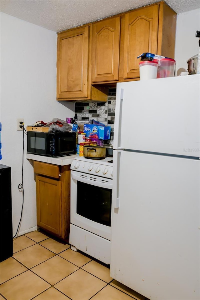 kitchen featuring light tile patterned floors, white appliances, tasteful backsplash, and a textured ceiling