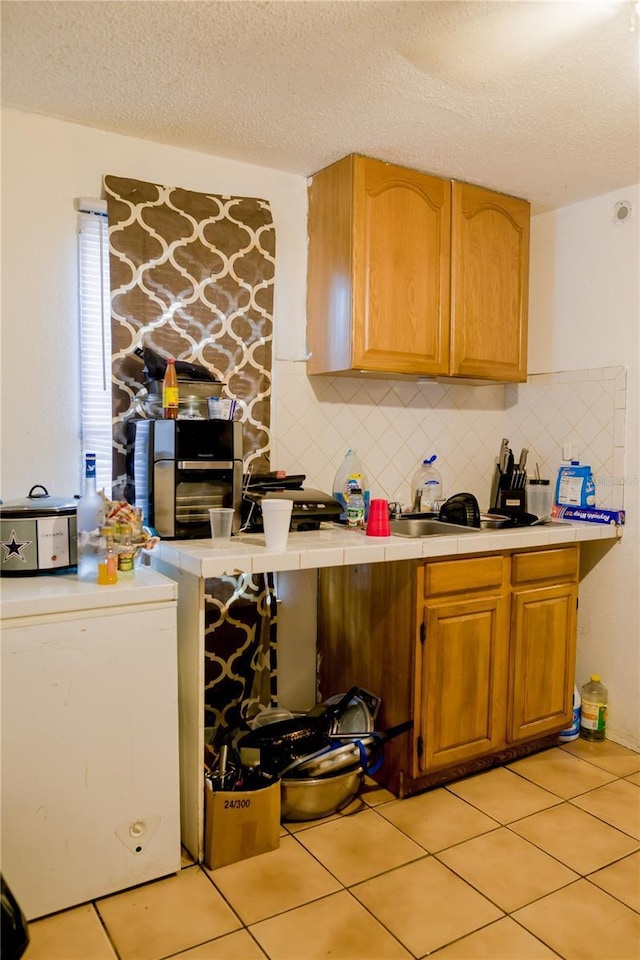 kitchen with tasteful backsplash, light tile patterned floors, a textured ceiling, and white refrigerator