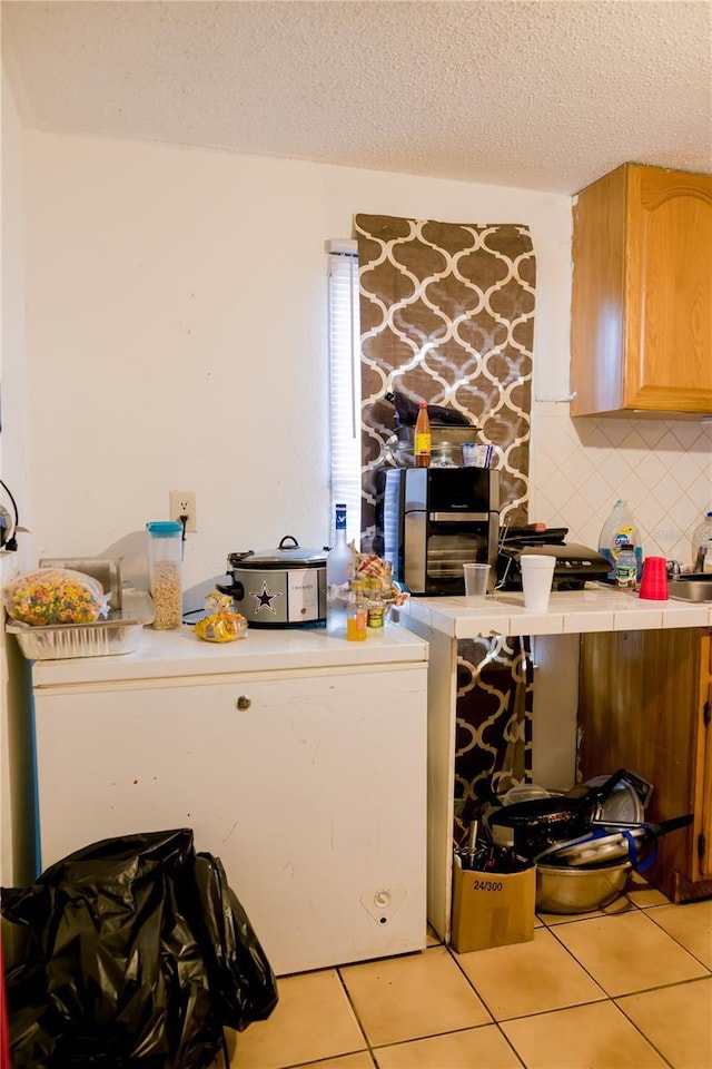 kitchen featuring decorative backsplash, light tile patterned floors, and a textured ceiling