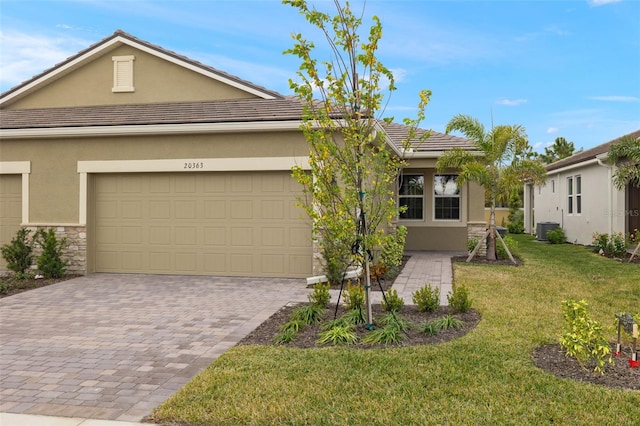 view of front of home with a garage, a front lawn, and central air condition unit