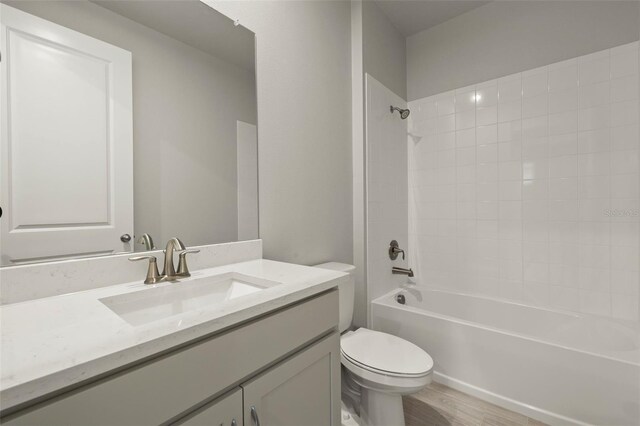 full bathroom featuring vanity, tiled shower / bath combo, toilet, and hardwood / wood-style flooring